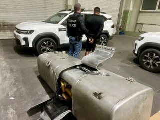 Резервоарът с отворения тайник, а на заден план служител и задържан мъж
